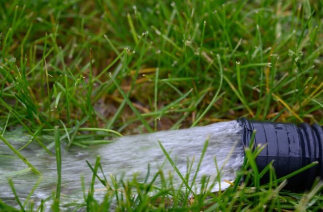 A residential sump pump discharging water away from a house