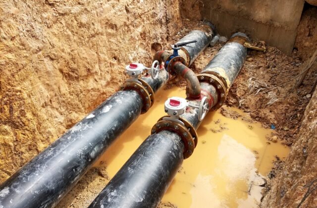 Crew laying underground utility pipe in an open trench
